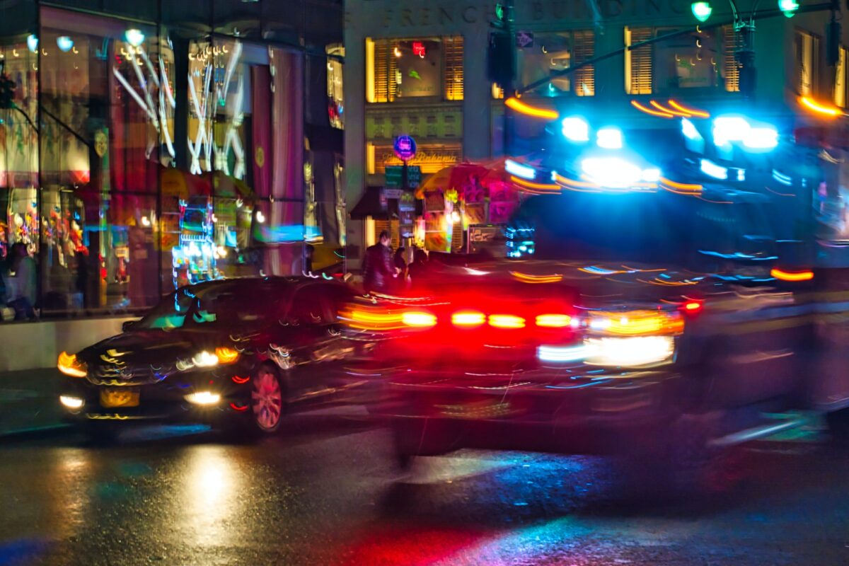 An emergency vehicle races down a busy city street